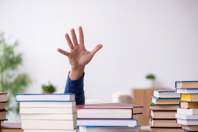 たくさんの参考書に手を伸ばしている人物