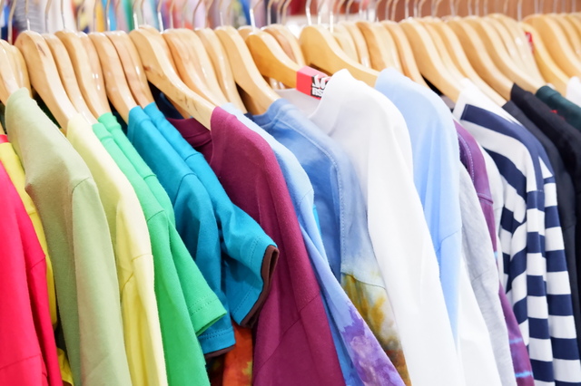 ハンガーにかけられて並んでいる色とりどりのたくさんの古着Tシャツ