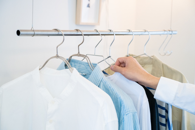 ハンガーラックにかかったシャツと商品を手に取る様子