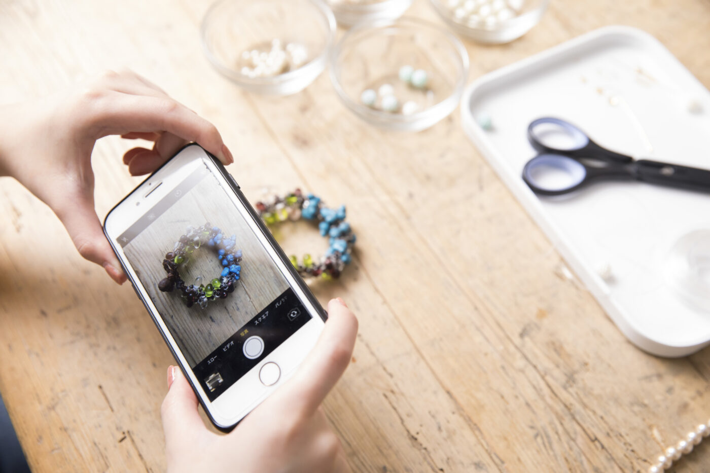 手作りアクセサリーをスマートフォンで撮影する様子