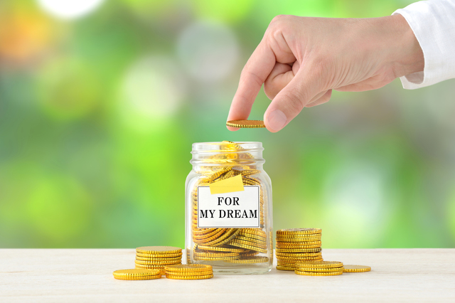 貯金箱にコイン（資金）を入れている手